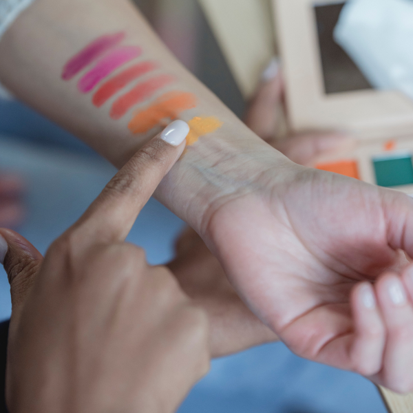 Braccio della make up artist con sfumature di colore e dito di una cliente che indica la sua scelta.