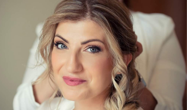 Sposa sorridente mentre un professionista le sistema i capelli in vista del grande giorno.